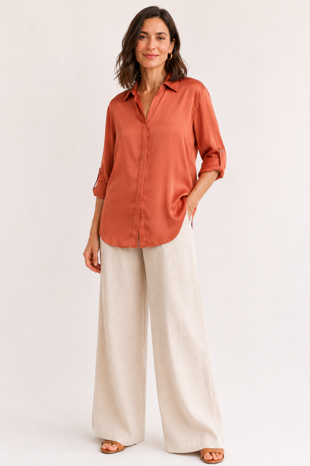Woman wearing a rust-colored shirt and white pants on a white background