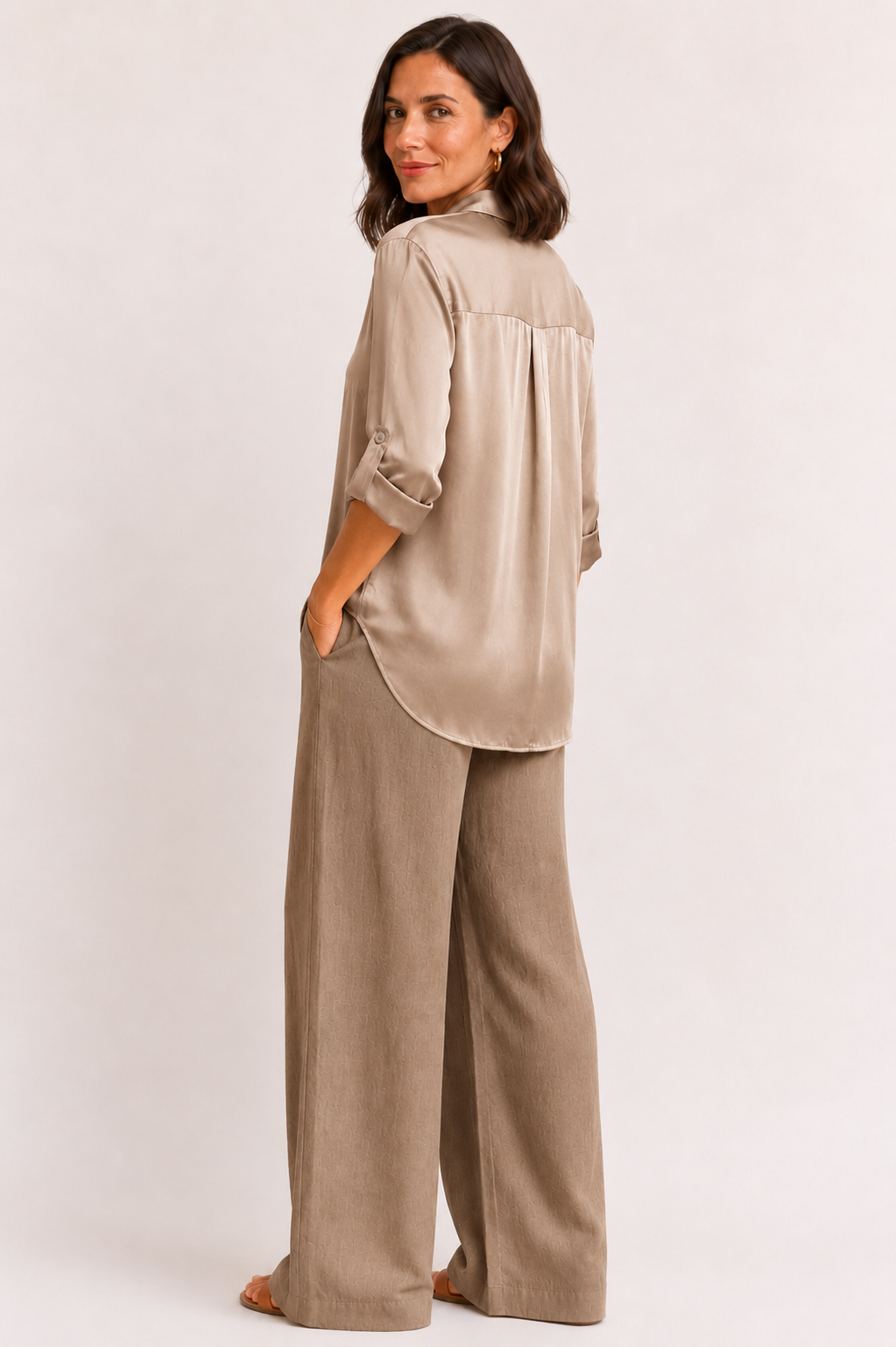 Woman wearing a beige blouse and wide-leg pants on a white background