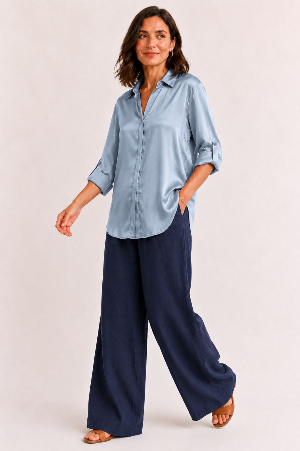 Woman wearing a light blue shirt and navy wide-leg pants on a white background
